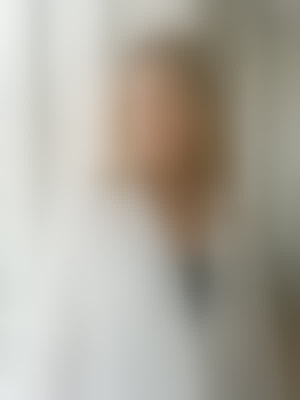 Amy in a white linen shirt by a tall window